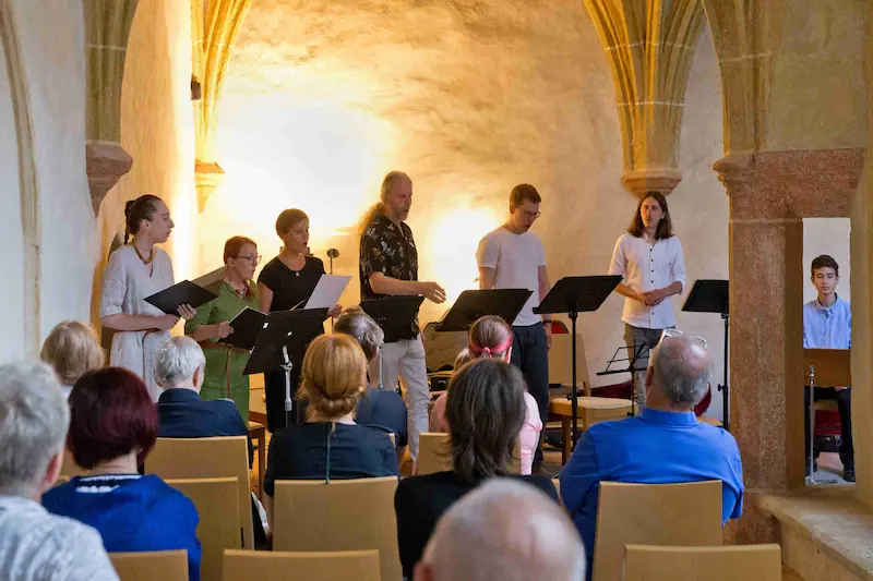 Sbor spívající v kostele před sedícím publikem